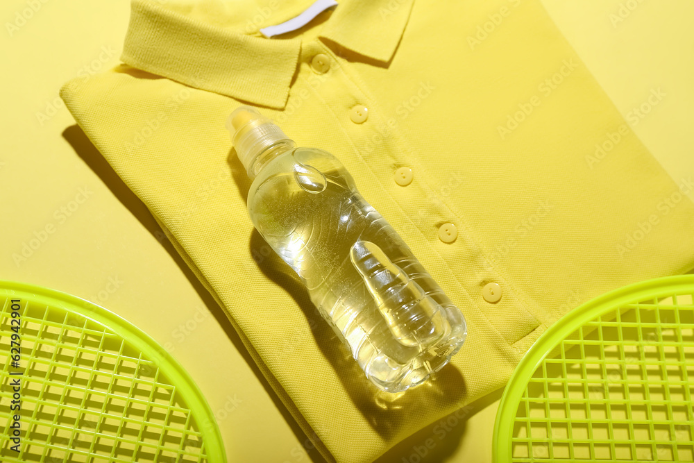 Bottle of water, t-shirt and tennis rackets on color background, closeup