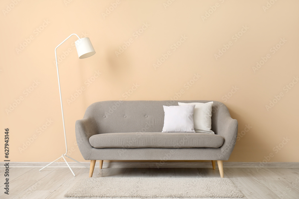 Grey sofa with white pillows near beige wall