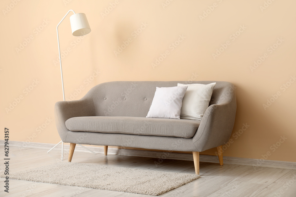 Grey sofa with white pillows near beige wall