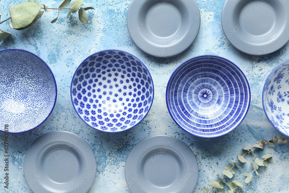 Set of different plates and eucalyptus branches on light blue table