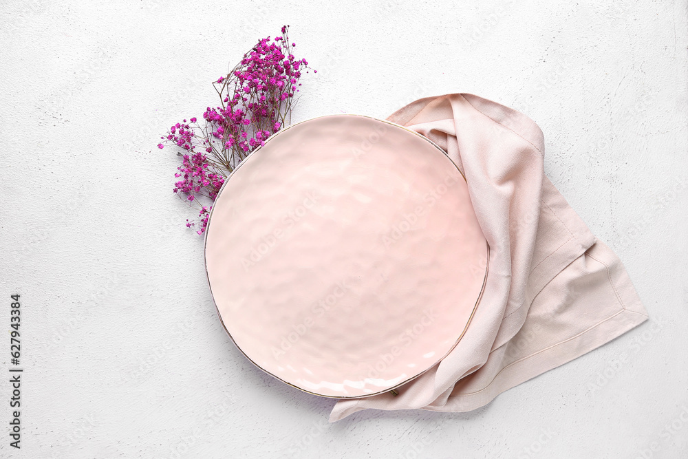 Clean plate with gypsophila flowers and napkin on white table