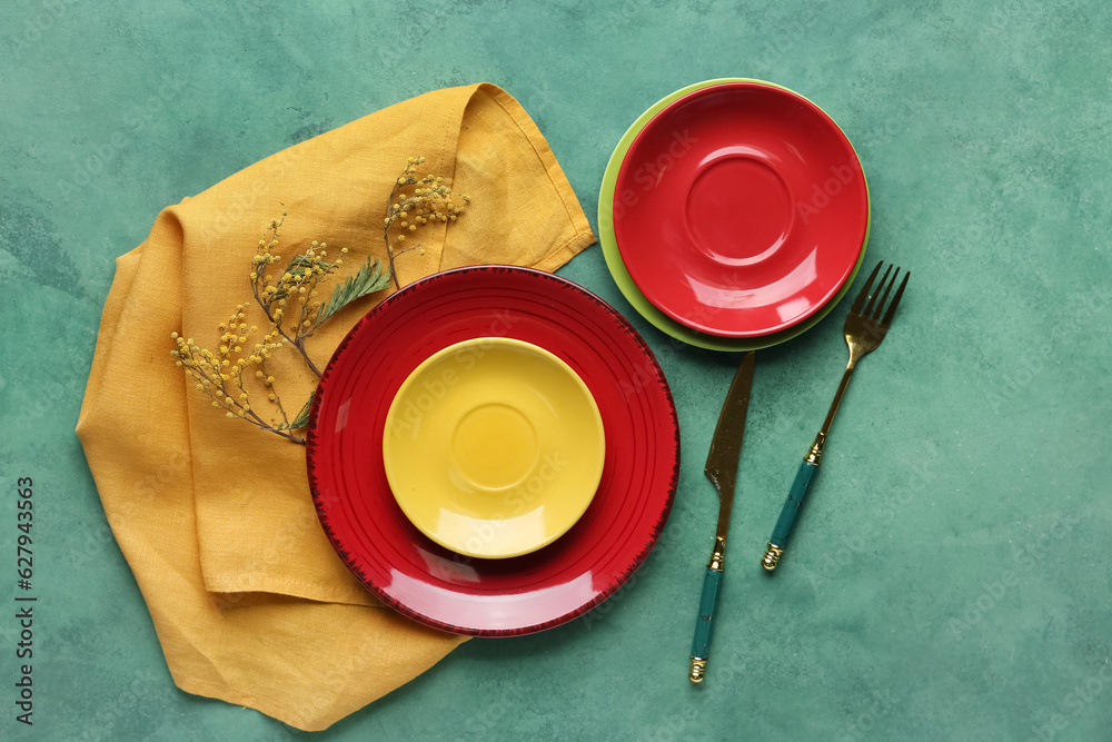 Clean plates, cutlery and floral decor on green table