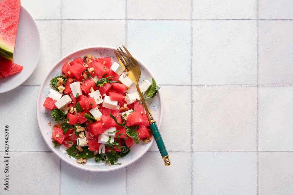 Plate of tasty watermelon salad on white tile background