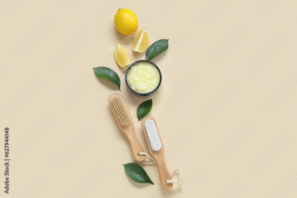 Bowl of lemon body scrub with massage brushes on beige background