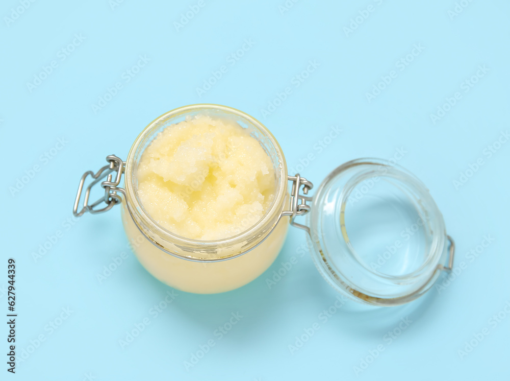 Jar of lemon body scrub on blue background