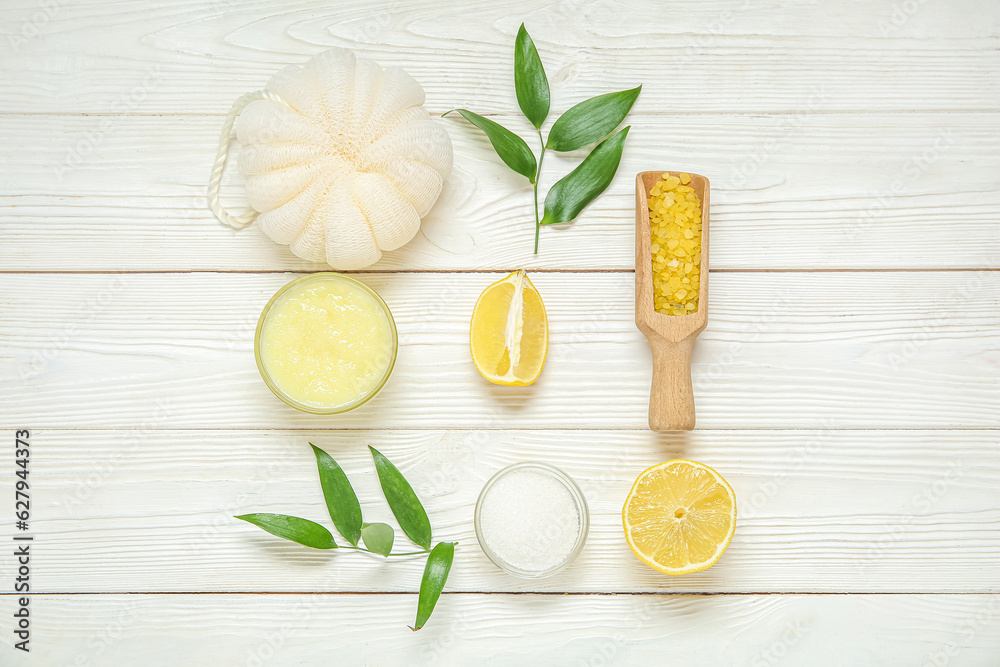 Bowl of lemon body scrub with bath sponge and sea salt on white wooden background