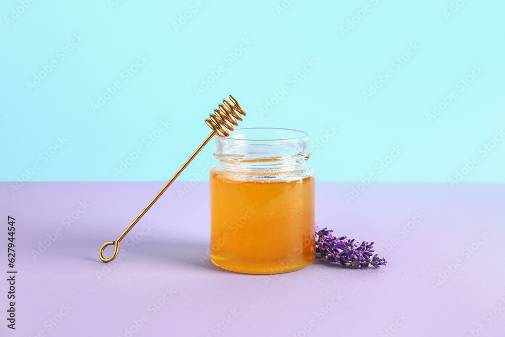 Jar of sweet lavender honey, dipper and flowers on lilac table