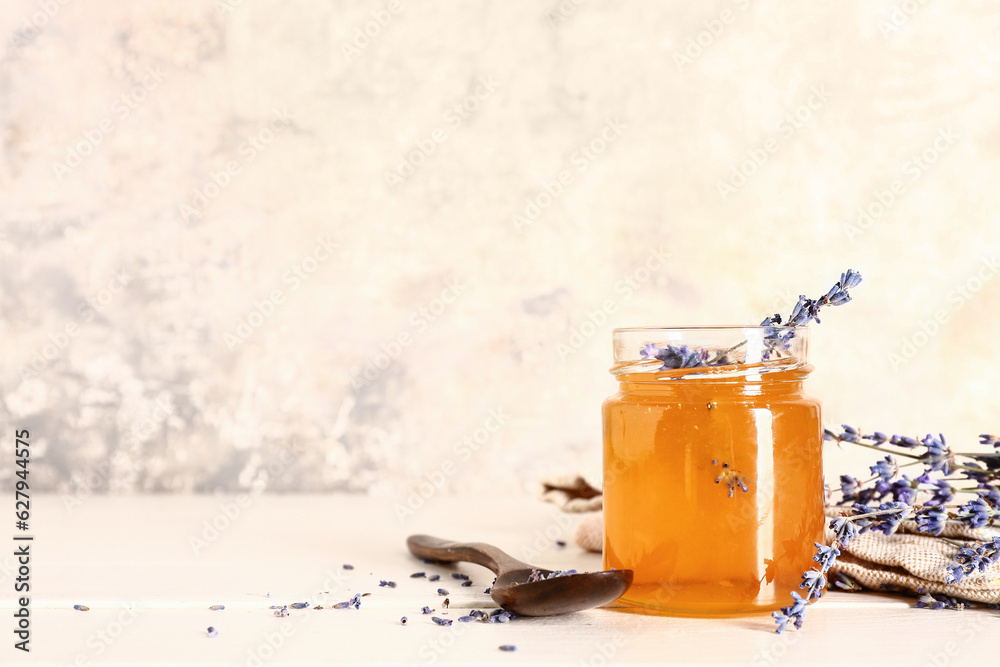 Jar of sweet lavender honey and flowers on white wooden table