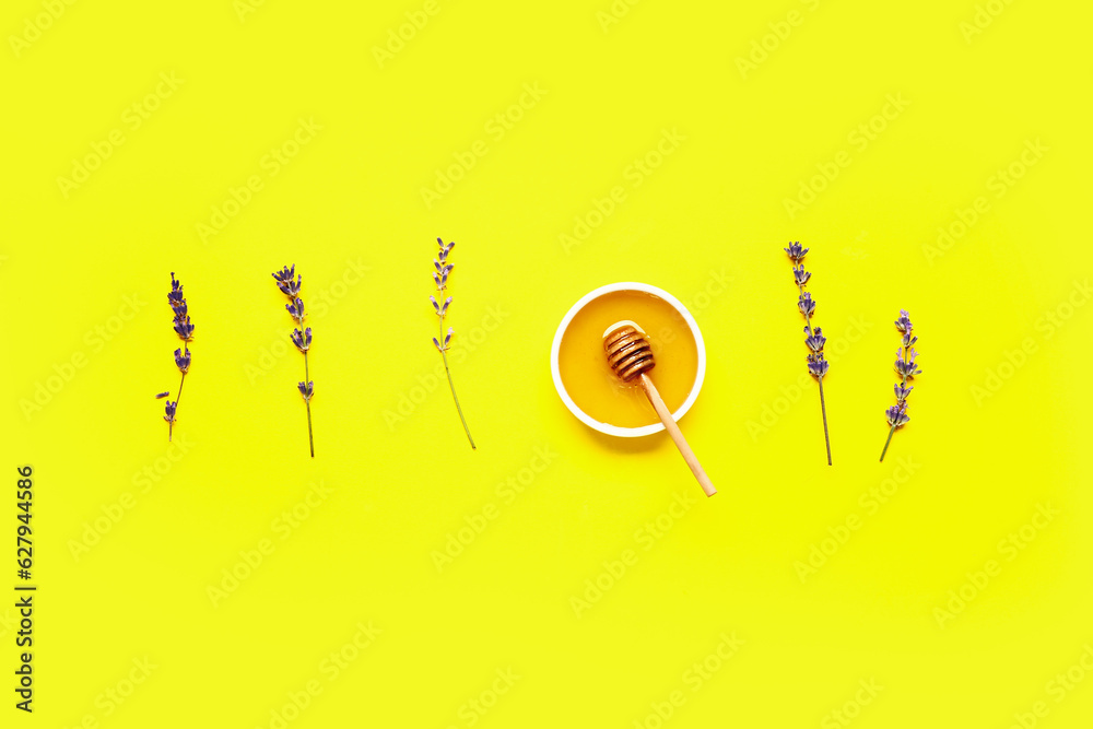 Bowl of sweet lavender honey, dipper and flowers on yellow background