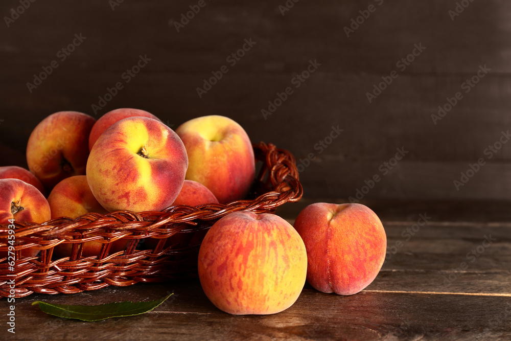 Wicker basket with sweet peaches on wooden background