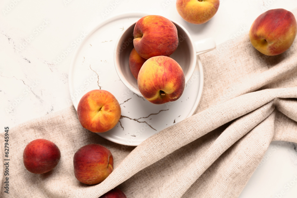 Cup with sweet peaches on white background