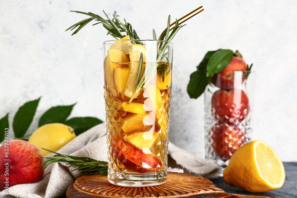 Wooden board with glass of fresh peach lemonade and rosemary on table