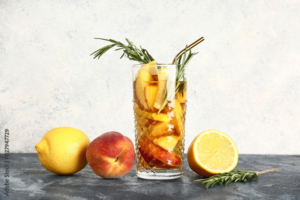 Glass of fresh peach lemonade with rosemary on blue table