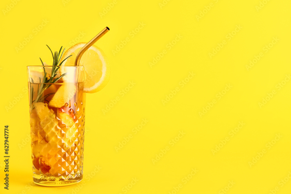 Glass of fresh peach lemonade with rosemary on yellow background