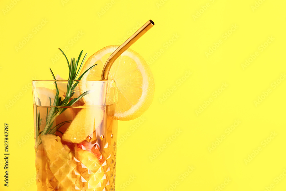 Glass of fresh peach lemonade with rosemary on yellow background