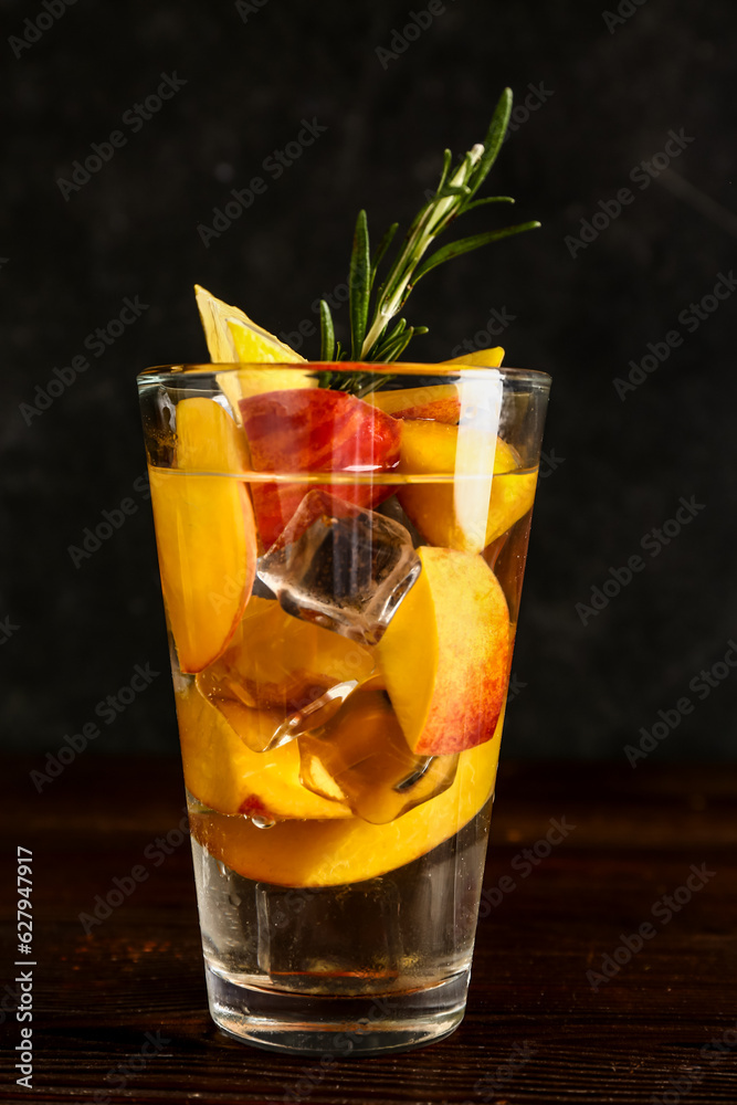 Glass of fresh peach lemonade with rosemary on wooden table