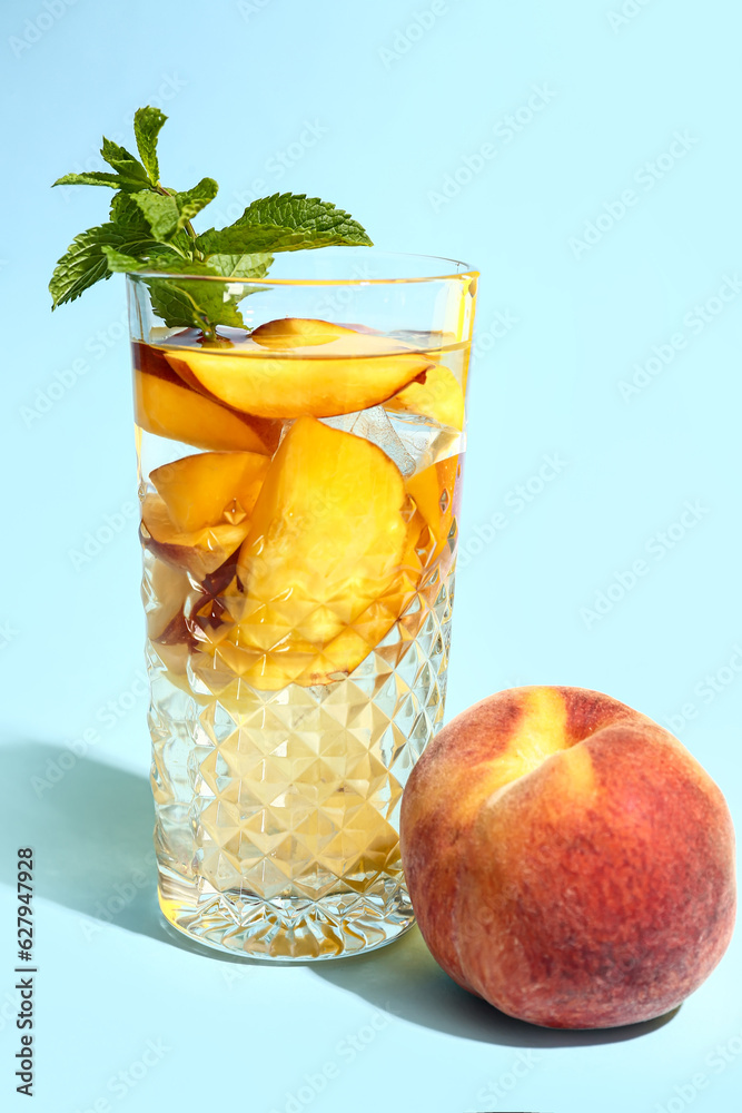 Glass of fresh peach lemonade with mint on blue background