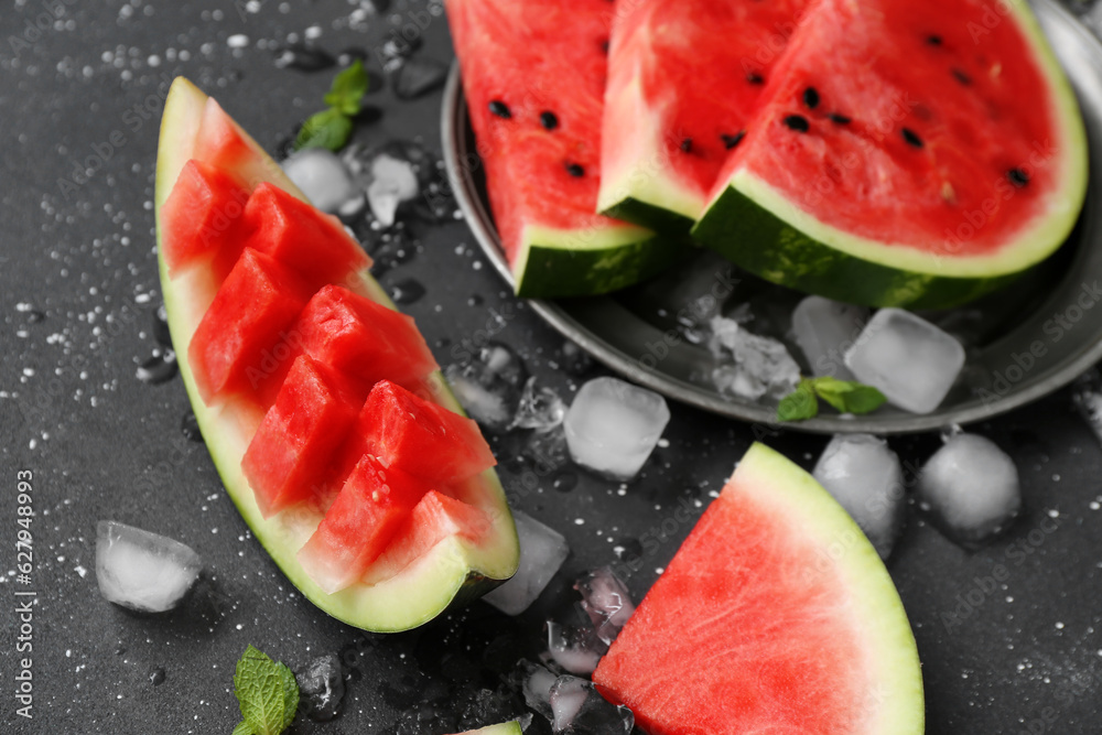 Plate with pieces of fresh watermelon and ice cubes on black background