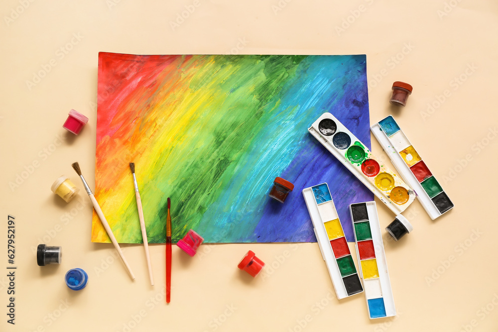 Brushes, paints and painting on beige background