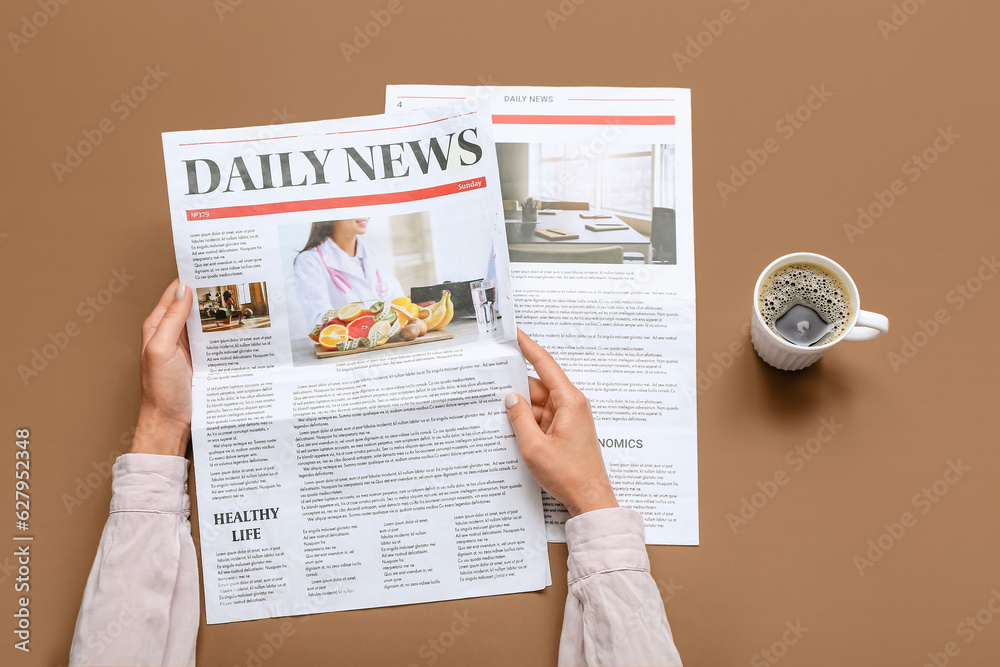 Woman reading newspaper with cup of coffee on brown background