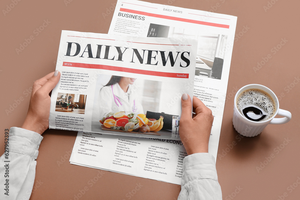 Woman reading newspaper with cup of coffee on brown background