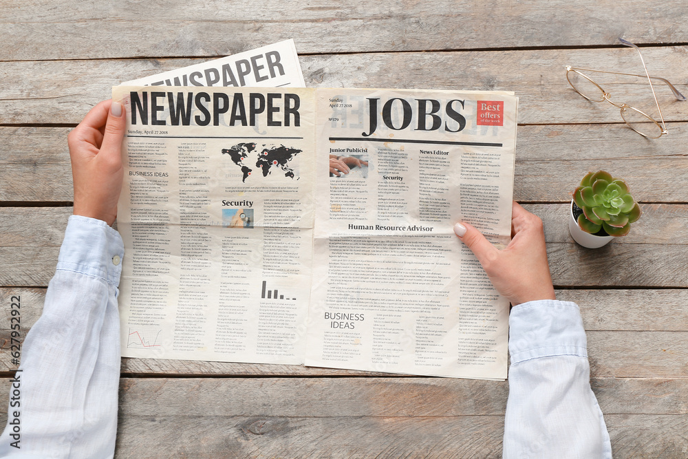 Woman reading newspaper on wooden background