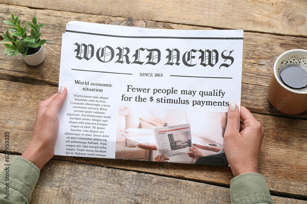 Woman reading newspaper with cup of coffee on wooden background