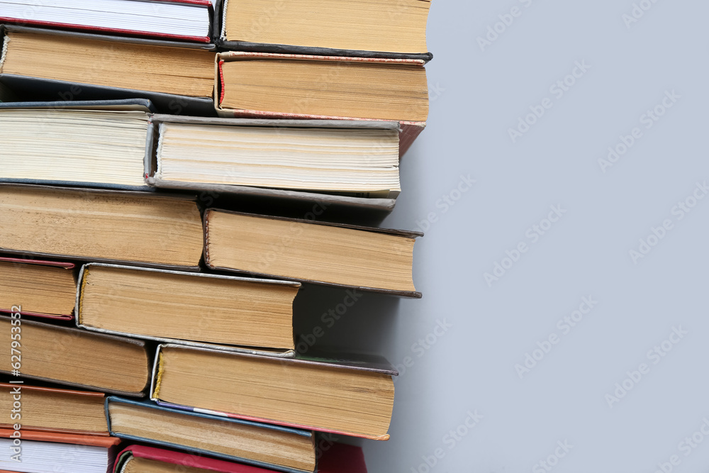 Many stacked books on grey background