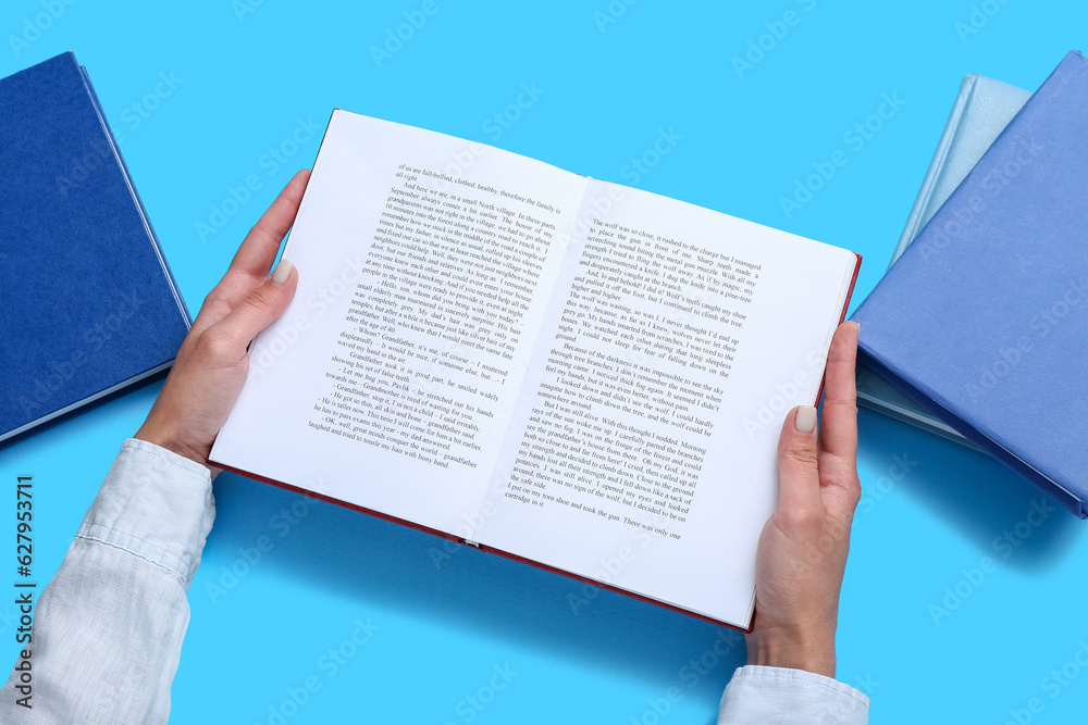 Female hands holding open book on blue background