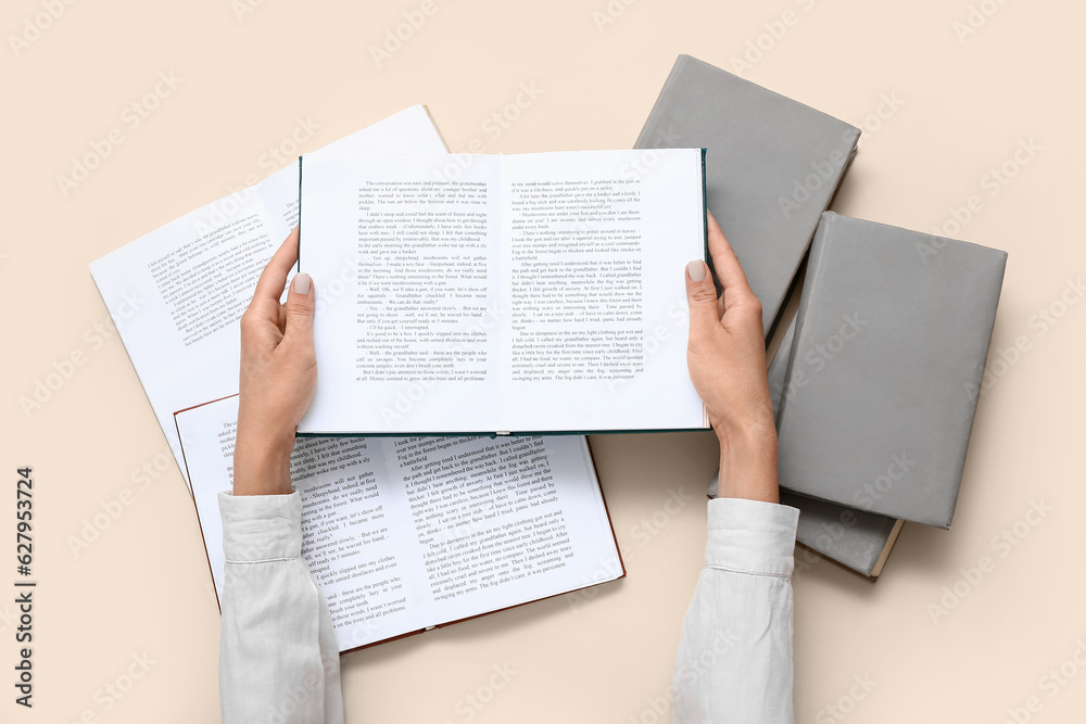 Female hands holding open book on beige background