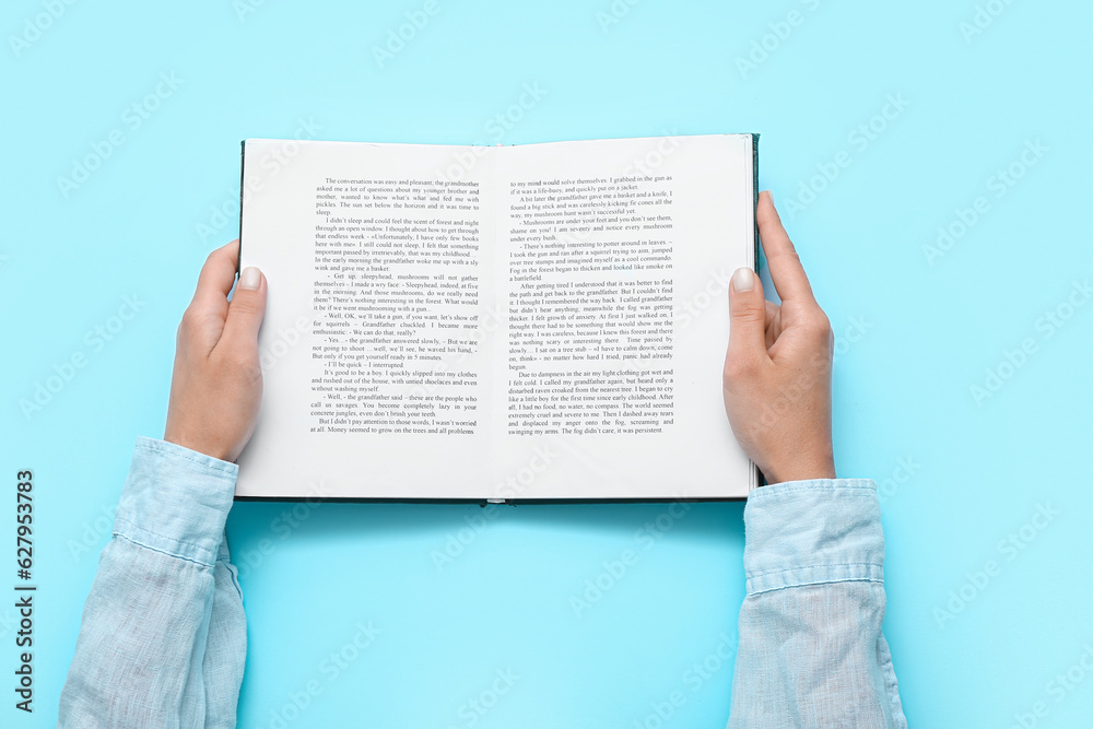 Female hands holding open book on blue background