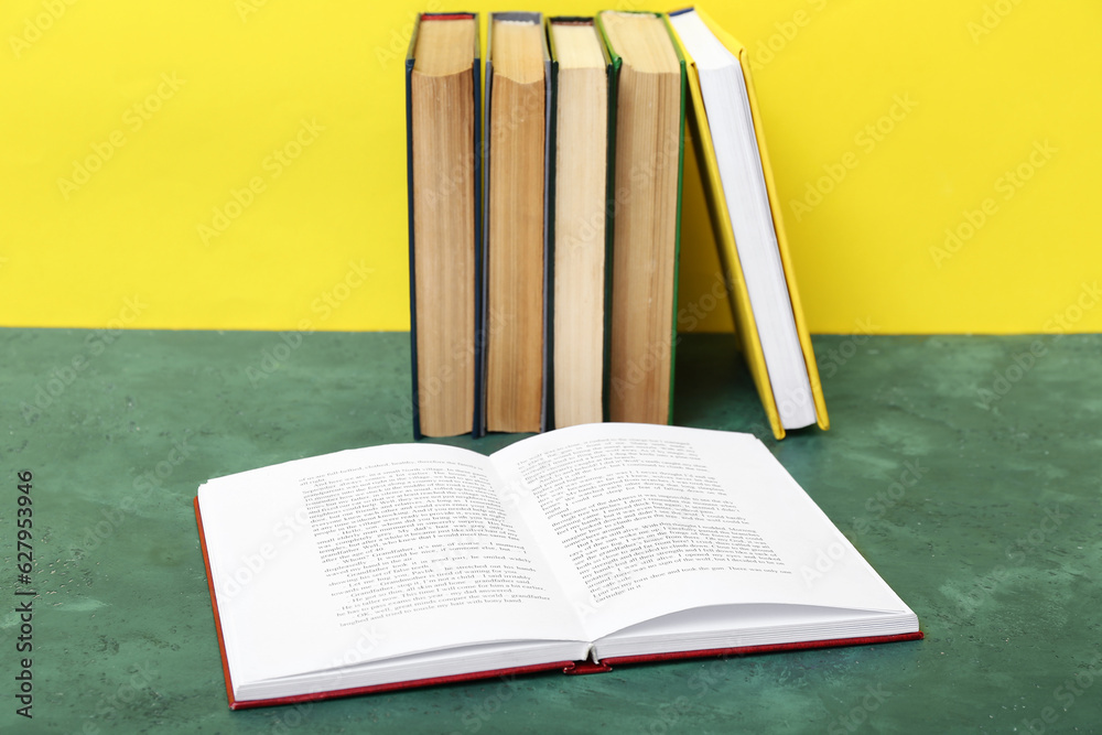 Open book on green table against yellow background