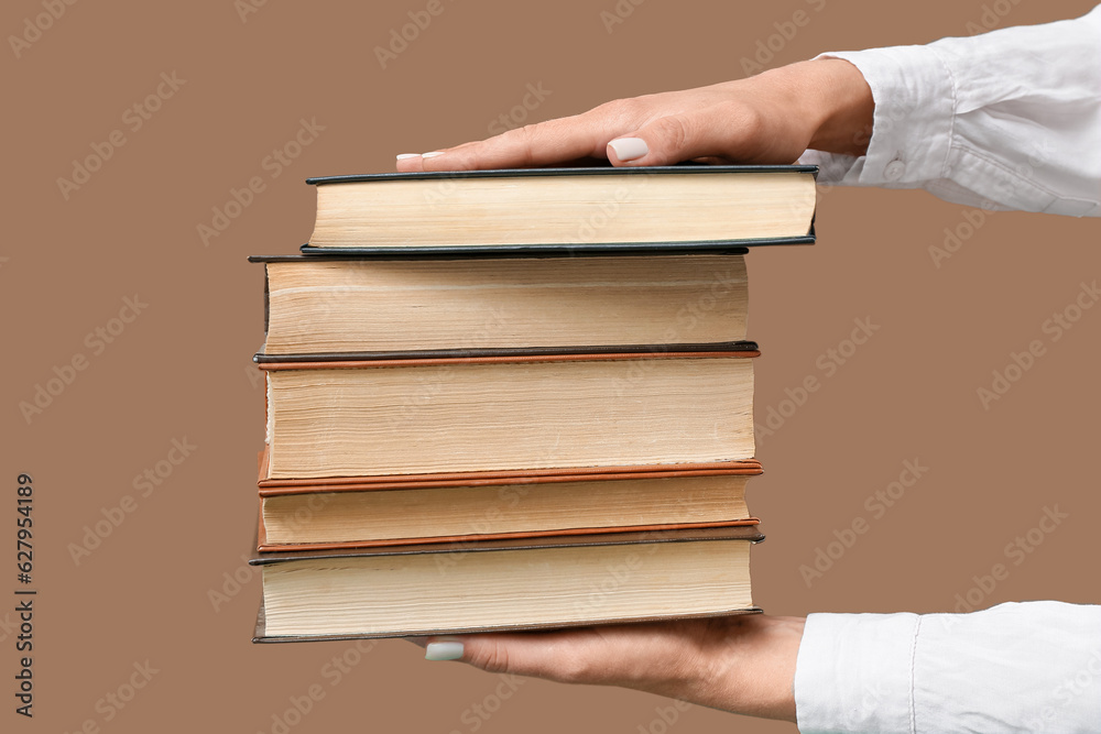 Female hands holding books on brown background