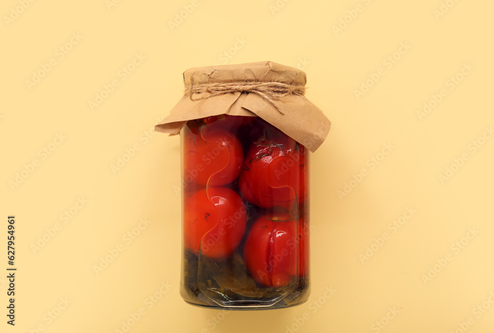 Jar with canned tomatoes on beige background