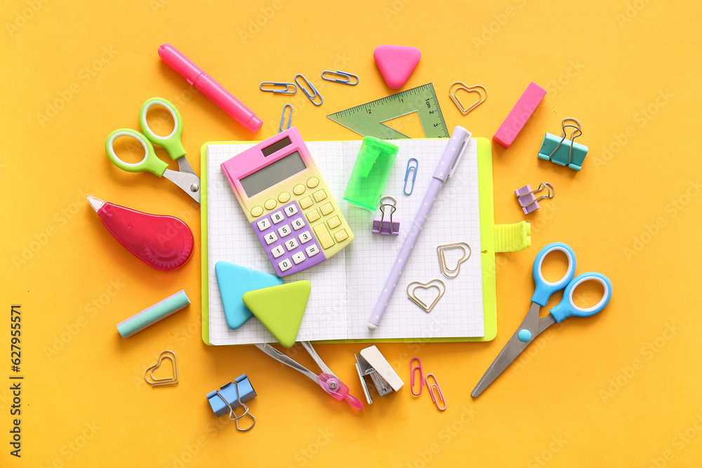 Different school stationery and notebook on orange background