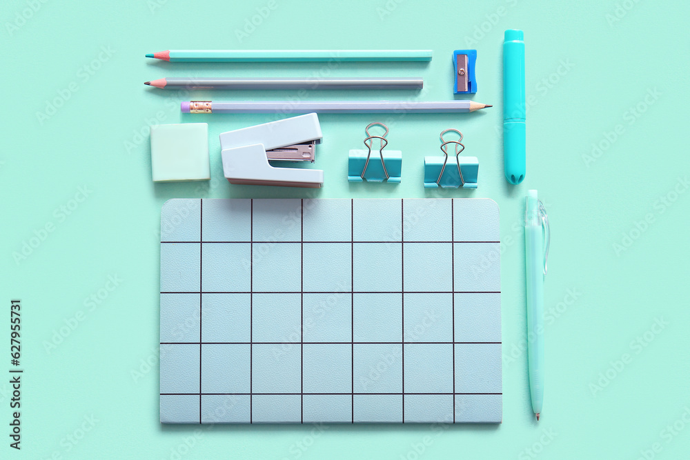 Different school stationery and notebook on turquoise background