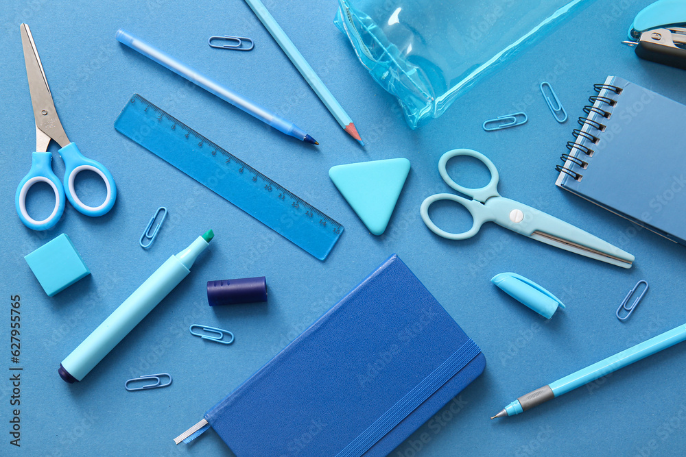 Different school stationery and notebooks on blue background