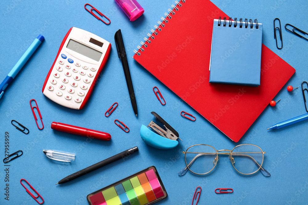 Different school stationery, notebooks and glasses on blue background