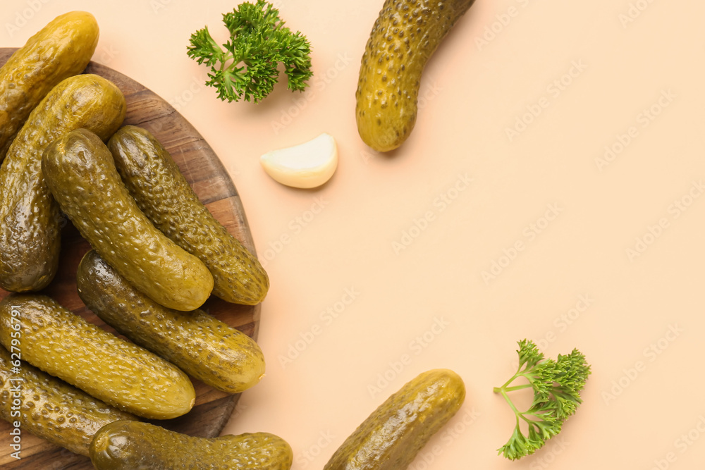 Wooden board with pickled cucumbers, parsley and garlic on orange background