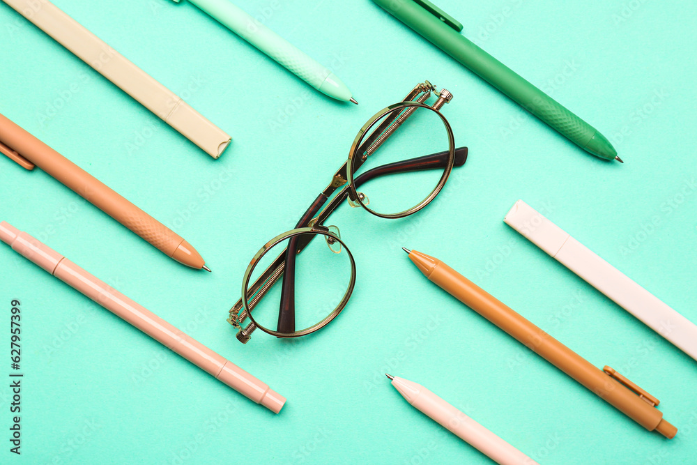 Stylish eyeglasses with stationery supplies on turquoise background