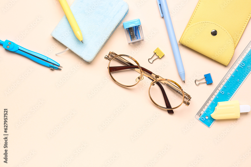 Stylish eyeglasses with stationery supplies on pink background