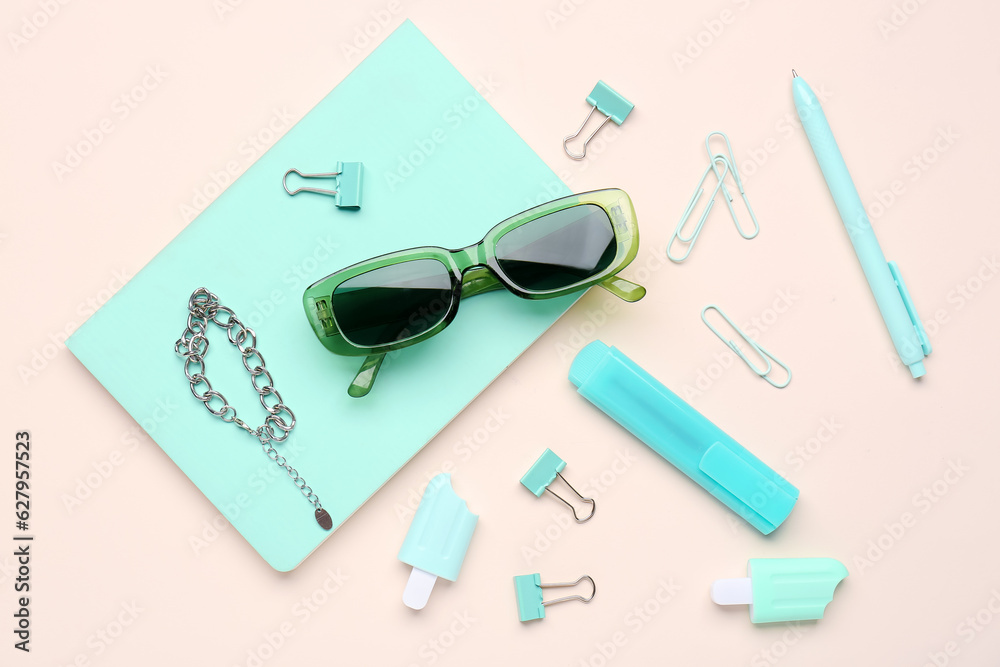 Stylish sunglasses with stationery supplies and chain bracelet on pink background