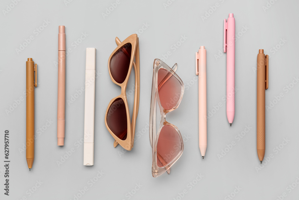 Stylish sunglasses with stationery supplies on grey background