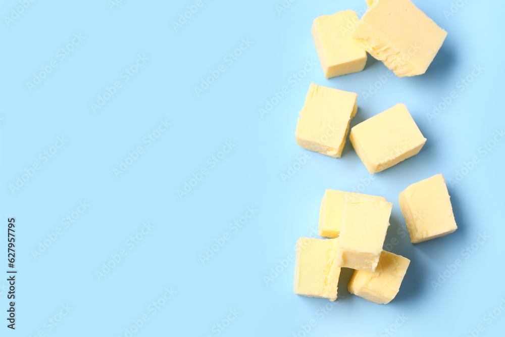 Pieces of fresh butter on blue background