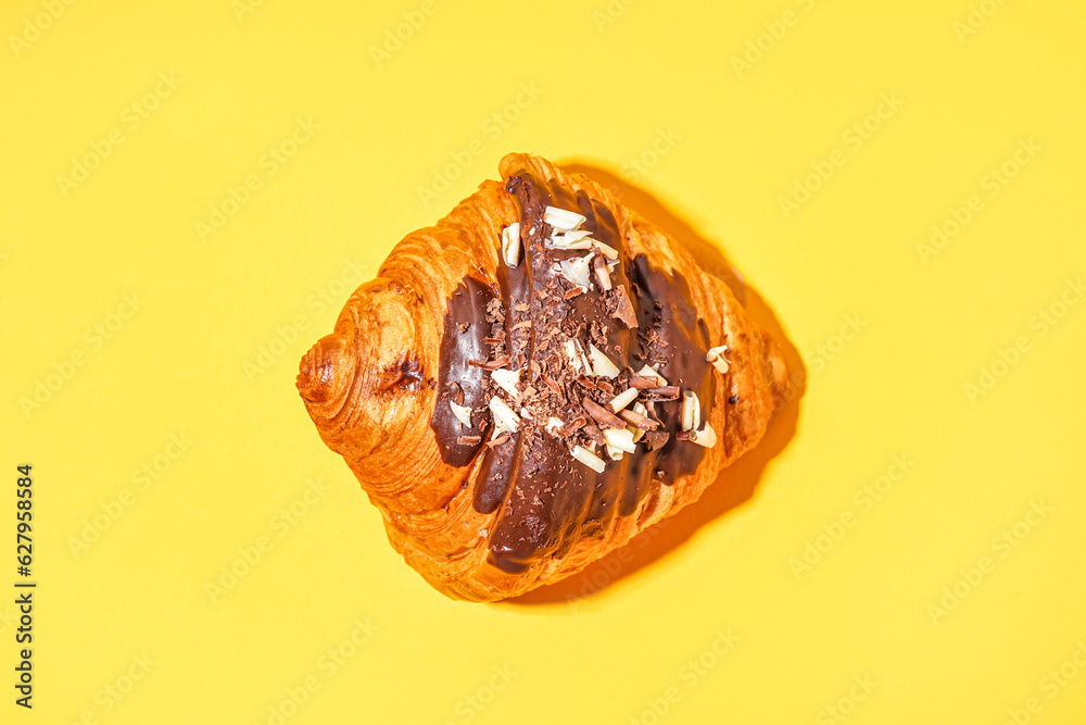 Sweet croissant with chocolate on yellow background