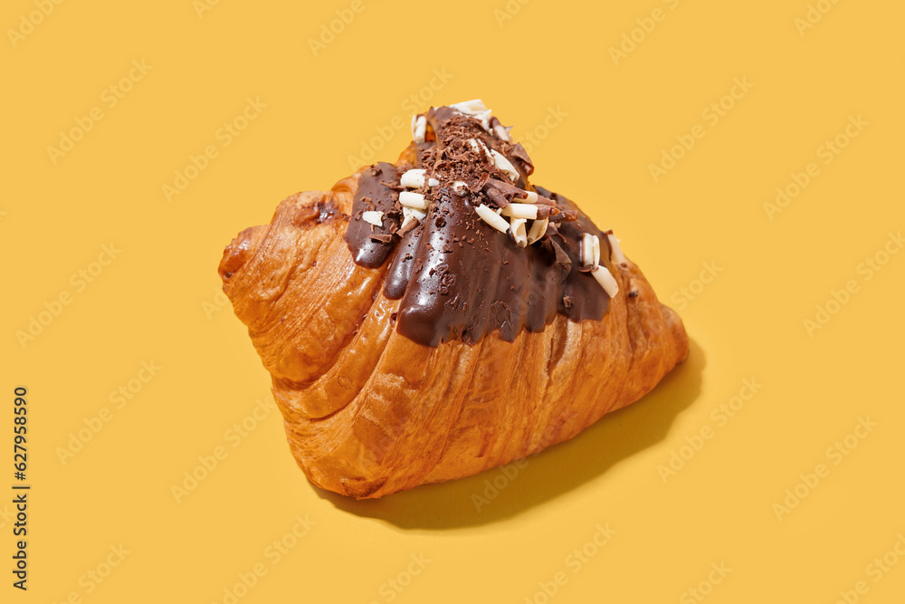 Sweet croissant with chocolate on yellow background