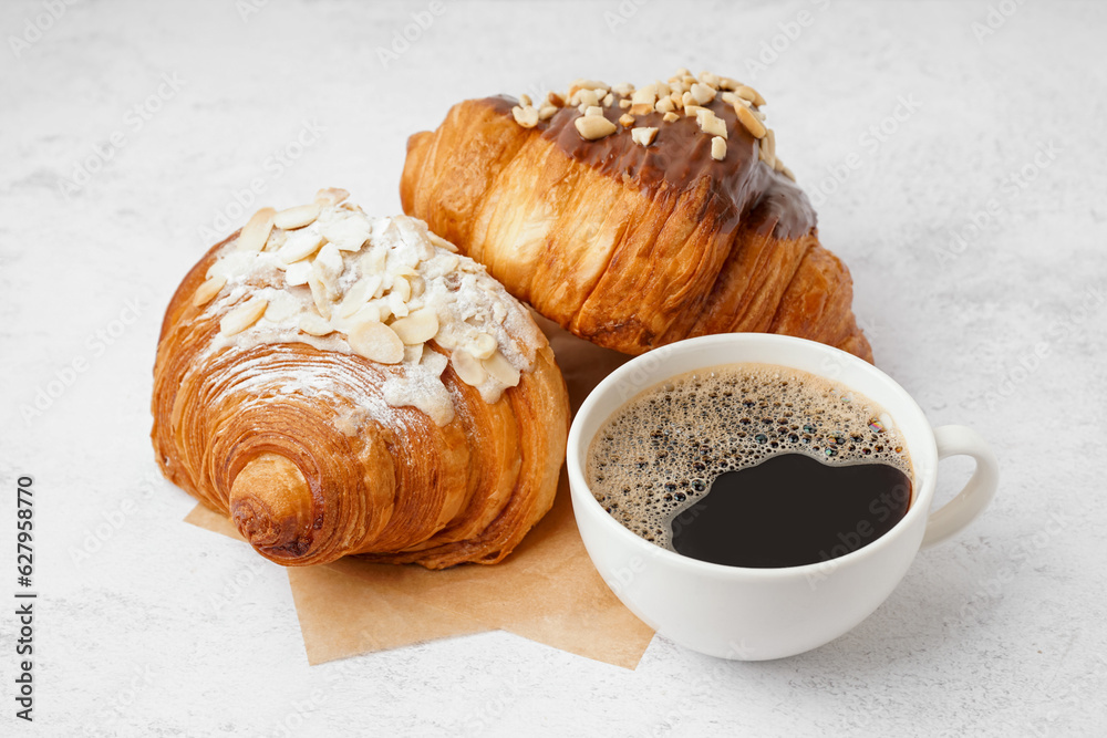 Different sweet croissants and cup of coffee on white background