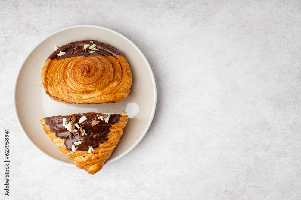 Plate of sweet croissant with chocolate on white background