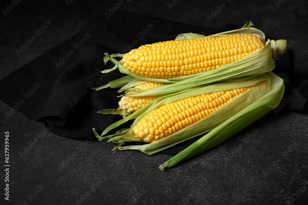 Fresh corn cobs on black background