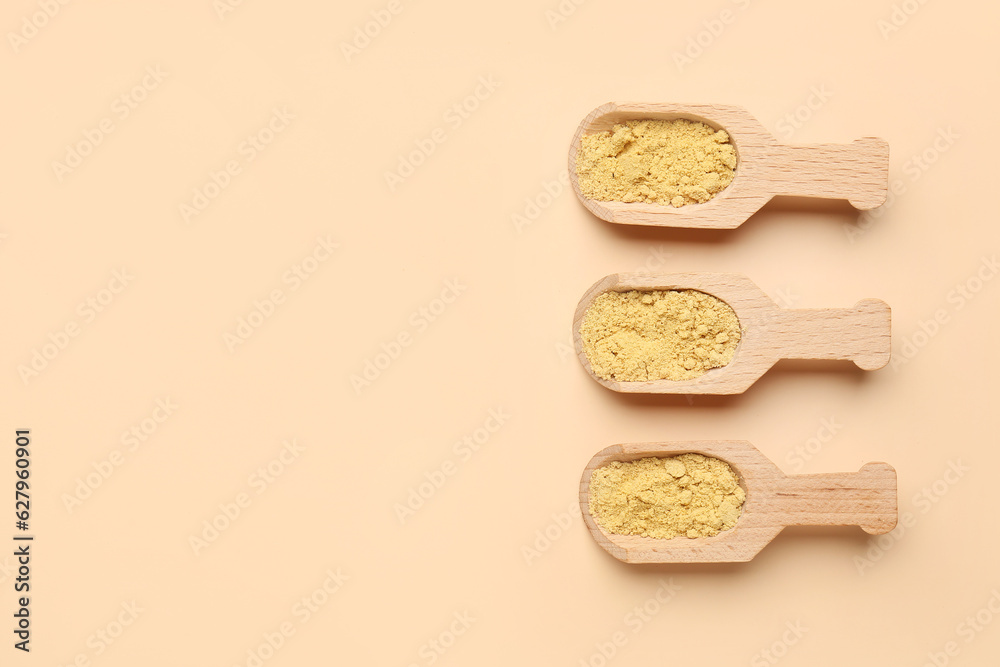 Wooden scoops with ginger powder on orange background